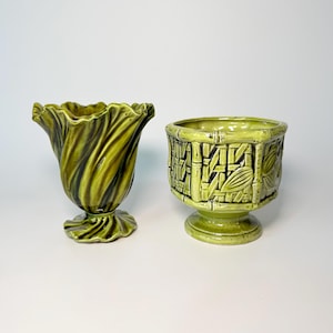 May include: Two ceramic vessels in shades of green. The left piece is a pedestal vase with a ruffled, flared rim and a spiraling, pleated body. The right piece is a footed planter featuring a textured, raised bamboo-style lattice pattern.