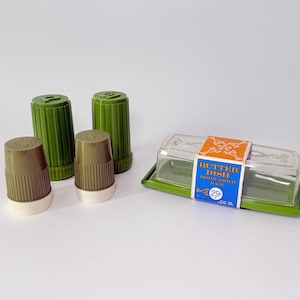 May include: A vintage kitchen set featuring olive green and brown salt and pepper shakers, and a butter dish with a clear lid. The set has a retro aesthetic, perfect for adding a touch of nostalgia to any kitchen.