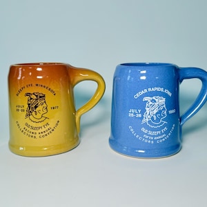 May include: Two ceramic beer steins. One is yellow and orange with text that reads "Sleepy Eye, Minnesota" and "Old Sleepy Eye Collectors Convention." The other is blue with "Cedar Rapids, Iowa" and "Old Sleepy Eye Collectors Convention."