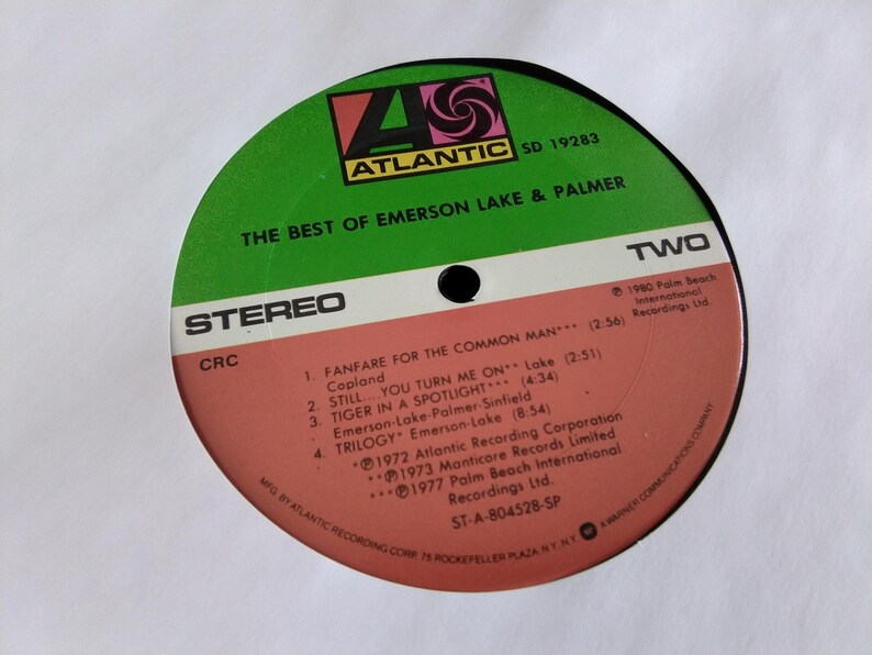 May include: A vintage vinyl record for "The Best of Emerson Lake & Palmer." The record label is green and red with the Atlantic Records logo. The tracklist includes "Fanfare for the Common Man" and "Trilogy."