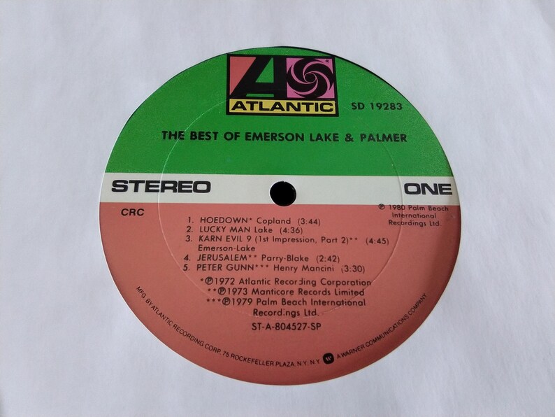 May include: A vinyl record for "The Best of Emerson Lake & Palmer" album. The record label is green and salmon-colored, with the Atlantic Records logo. The tracklist includes "Hoedown," "Lucky Man," and "Karn Evil 9."