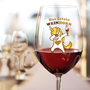 Puede incluir: Una copa de vino transparente con un diseño de unicornio dorado que dice "Das Letzte WEINHORN". El unicornio lleva gafas de sol y sostiene una copa de vino.