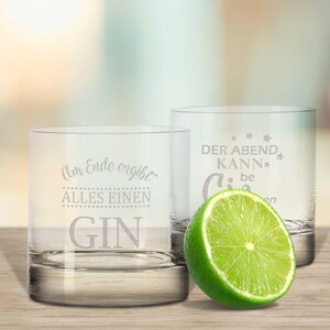 Peut inclure: Deux verres à whisky en verre transparent avec une inscription humoristique gravée sur chacun. Le verre de gauche dit "Am Ende ergibt alles einen Gin". Le verre de droite dit "Der Abend kann Gin be". Une tranche de citron vert se trouve devant les verres.