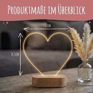 May include: A heart-shaped LED light with a warm glow, mounted on a rectangular wooden base. The text "PRODUKTMA&szlig;E IM &Uuml;BERBLICK" appears at the top. Arrows indicate dimensions of 17 cm in width and 14.5 cm in height for the heart light.