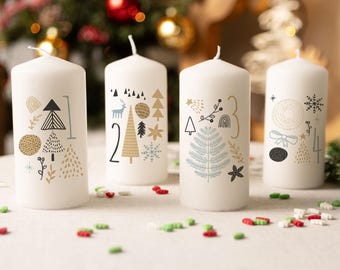 Könnte beinhalten: Vier weiße Stumpenkerzen mit festlichen Designs und den Zahlen 1-4. Jede Kerze zeigt eine einzigartige Illustration von Bäumen, Schneeflocken und anderen weihnachtlichen Elementen in Gold, Schwarz und Blau. Rote und grüne Streusel sind um die Kerzen verstreut.