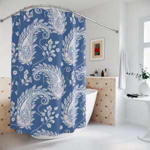 May include: A blue paisley shower curtain with a repeating pattern of large, stylized paisley shapes in white, light blue, and pink. The curtain is hanging in a bathroom setting, adding a decorative touch to the space.