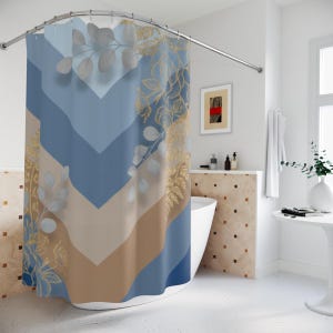 May include: A blue, tan, and white shower curtain with a chevron pattern. The curtain features gold and white botanical accents. The shower curtain is hanging from a curved metal rod.