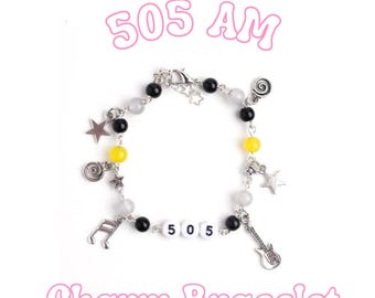 May include: A silver-toned charm bracelet featuring black, yellow, and translucent white beads. The bracelet includes metal charms shaped like stars, musical notes, and a guitar, with white letter beads spelling out 505 in the center.