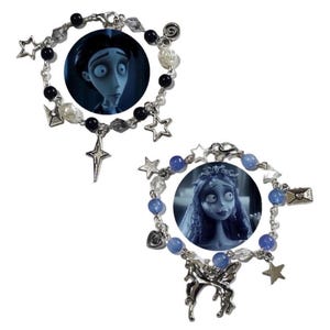 Puede incluir: Dos pulseras de cuentas con imágenes de personajes de la película animada. Una pulsera tiene cuentas blancas y negras, dijes de estrella y un colgante de cruz. La otra tiene cuentas azules, dijes de estrella y un dije de hada.