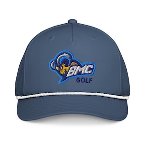 K&ouml;nnte beinhalten: Eine marineblaue Baseballkappe mit einem wei&szlig;en Kordeldetail an der Basis der Krone. Die Vorderseite zeigt ein gesticktes Logo eines gelb-blauen Widderkopfes mit dem Text BMC GOLF in wei&szlig;er und blauer Schrift auf blauem Hintergrund.