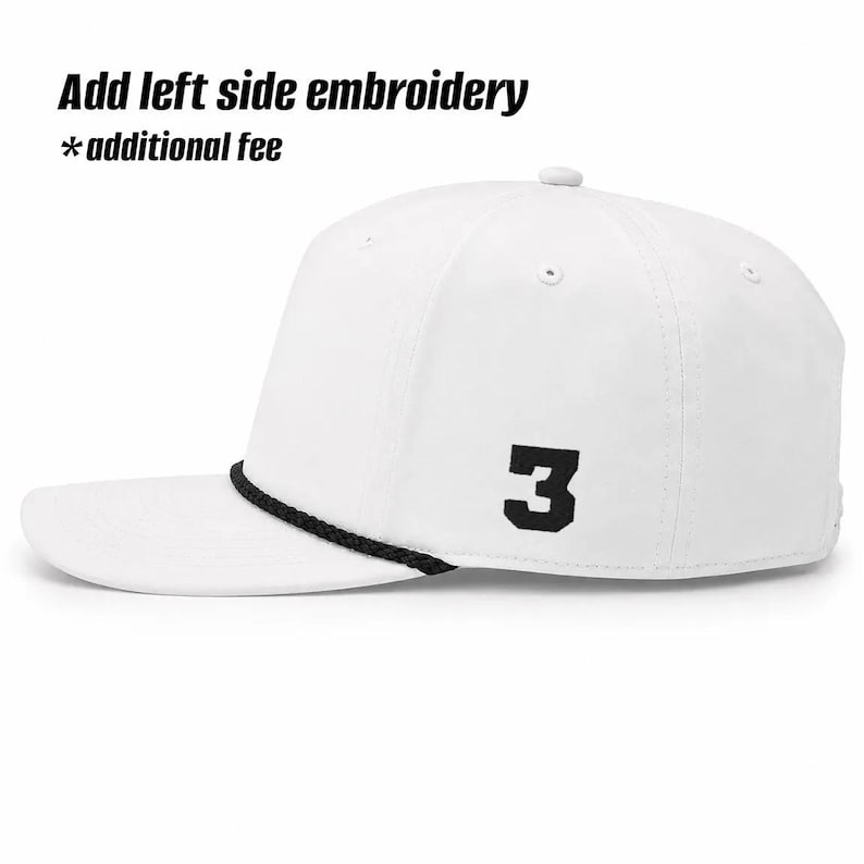 K&ouml;nnte beinhalten: Eine wei&szlig;e Baseballkappe mit einer schwarzen Zahl 3, die an der Seite aufgestickt ist, und einer schwarzen Kordel an der Basis der Krone. Der Text Add left side embroidery *additional fee ist &uuml;ber der Kappe auf wei&szlig;em Grund zu sehen.