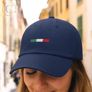 May include: A navy blue baseball cap featuring an embroidered Italian flag. The flag design is a horizontal tricolor of green, white, and red. The cap has a curved brim and a structured crown, suitable for casual wear.