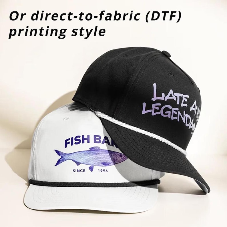 K&ouml;nnte beinhalten: Eine wei&szlig;e Baseballkappe mit blauem Fischmotiv und dem Text "FISH BAN SINCE 1996" sowie eine schwarze Baseballkappe mit dem violetten Text "LATE AND LEGENDARY", mit wei&szlig;er Kordel am Schirm und dem Text "Or direct-to-fabric (DTF) printing style".