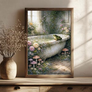 May include: A framed art print depicts a vintage bathtub scene. The tub is surrounded by flowers and greenery, with a green frog perched on the edge. The artwork has a whimsical, fairytale aesthetic, with mushrooms and a window in the background.