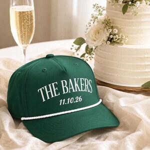 Op de afbeelding: Een donkergroene honkbalpet met een wit koorddetail over de klep. De voorkant van de pet toont de witte tekst THE BAKERS boven de datum 11.10.26 in een strak, vet lettertype. De pet is gemaakt met een gestructureerde kroon en ventilatiegaatjes.