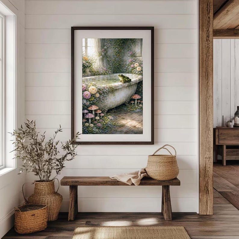 May include: A framed art print depicts a vintage bathtub scene. The tub is surrounded by flowers, mushrooms, and greenery, with a frog perched on the edge. The artwork is displayed above a wooden bench with a woven basket and a neutral-colored rug.