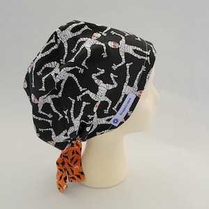 Wende chirurgischer Hut von BrightCaps, Schwarze Halloween Mumie mit Orangen Fledermäusen und Monden
