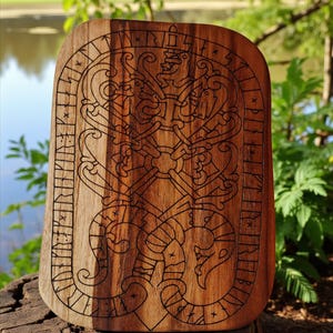Könnte beinhalten: Rechteckige Holzplakette mit aufwendigen Schnitzereien eines stilisierten Designs und Runeninschriften. Die Plakette besteht aus hellbraunem Holz, die Schnitzereien sind dunkelbraun. Präsentiert auf einem Baumstumpf.