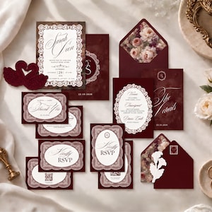 May include: A wedding stationery suite in deep burgundy featuring white lace-style borders, floral envelope liners, and swan-shaped cutouts. The cards include text such as Sarah & Sean, Thank You, and RSVP, with elegant script typography on a dark background.