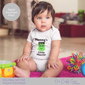 May include: A baby wearing a white onesie with the text "Mommy's Little Monster" and a green Frankenstein's monster graphic. The baby is sitting on a pink mat with toys nearby. A digital download graphic is in the background.