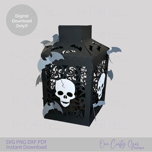 Puede incluir: Linterna de papel negra con diseños recortados, calaveras y murciélagos. La linterna tiene forma rectangular con una parte superior y está decorada con murciélagos grises. El texto "Digital Download Only!!!" está en un círculo.