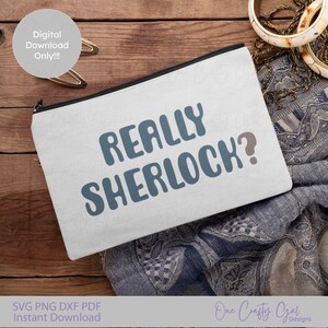 May include: A white zippered pouch with the text "REALLY SHERLOCK?" in blue and brown. The pouch is on a wooden surface with a patterned scarf and jewelry.