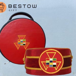 Puede incluir: Un estuche redondo rojo con asa negra y un sombrero rojo a juego. Ambos artículos presentan un emblema dorado con un diseño geométrico y el texto "BESTOW GIFT". El estuche tiene cierre de cremallera.