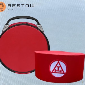 Op de afbeelding: Een rode ronde koffer met een zwarte handgreep en een rode fez met een wit embleem. De koffer heeft zilveren accenten. De fez heeft een witte cirkel met een rode driehoek en een horizontale lijn. De tekst "BESTOW GIFT" staat linksboven.
