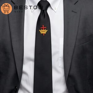 May include: Black tie with a gold crown and red cross emblem. The tie is worn with a white dress shirt and a dark gray suit jacket. The logo "BESTOW GIFT" is in the upper left corner.