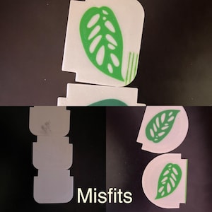 May include: White and green plant-themed decorative pieces. The design features a green leaf with cut-out details on a white background. The word "Misfits" is printed in white at the bottom of the image.