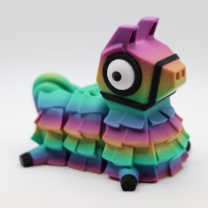 May include: A colorful llama figurine with a rainbow gradient design. The llama has a black bridle and large white eyes. The figurine is made of plastic and has a layered, textured appearance.