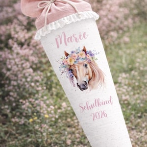 May include: A white cylindrical gift bag with a pink drawstring closure and a ruffled lace trim. The bag features a watercolor illustration of a horse's head wearing a floral crown, with the name "Marie" and the year "2026" printed on it.