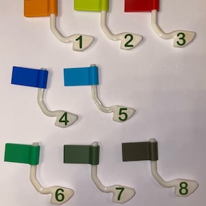 May include: Eight colorful flags with numbers 1 through 8 on a white background. The flags are attached to white plastic holders.