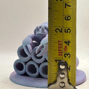 Puede incluir: Escultura impresa en 3D de un cangrejo morado claro con una base de arrecife de coral. El cangrejo mide aproximadamente 5 cm de altura. La escultura presenta un dise&ntilde;o detallado con una superficie texturizada y est&aacute; sobre un fondo liso.