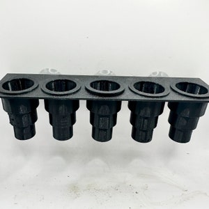 May include: A black plastic plant propagation station with five individual pots. The pots are stacked in a tiered design, creating a vertical growing system.