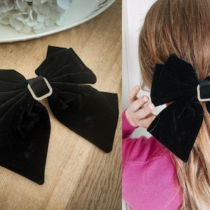May include: A large black velvet bow with a rhinestone-encrusted buckle. The bow is tied in a large, loose knot and is perfect for adding a touch of elegance to any outfit.