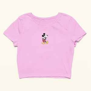 Peut inclure: Un t-shirt rose p&acirc;le &agrave; manches courtes et &agrave; ourlet court, avec une image de Mickey Mouse au centre.