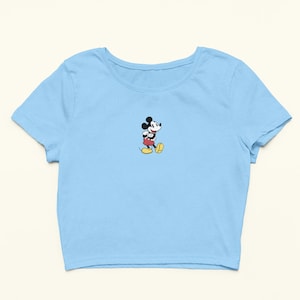 Peut inclure: Un t-shirt court bleu ciel avec une image de Mickey Mouse en dessin anim&eacute; au centre.