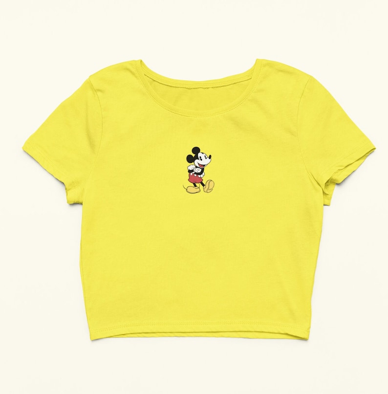 Peut inclure: Un t-shirt jaune court avec une petite image brod&eacute;e de Mickey Mouse marchant.