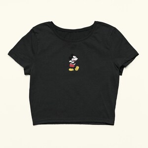 Peut inclure: T-shirt noir &agrave; manches courtes et coupe courte avec une petite image brod&eacute;e de Mickey Mouse au centre.