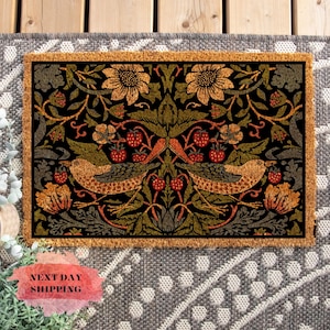 May include: A brown coir doormat with a black background and a colorful floral pattern featuring birds, leaves, and berries. The pattern is symmetrical and has a vintage aesthetic.