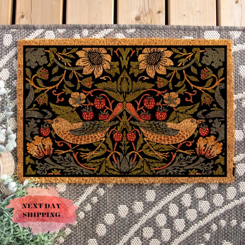 May include: A brown coir doormat with a black background and a colorful floral pattern featuring birds, leaves, and berries. The pattern is symmetrical and has a vintage aesthetic.