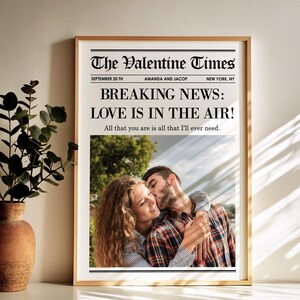 May include: A framed print designed as a newspaper front page, titled "The Valentine Times." The headline reads "BREAKING NEWS: LOVE IS IN THE AIR!" with a photo of a couple. The date is September 20th, with names "Amanda and Jacop."
