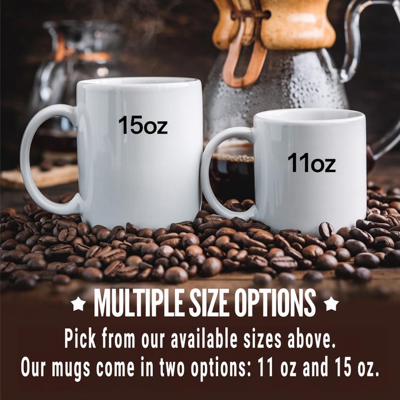 May include: Two white ceramic mugs with black text. The larger mug says "15oz" and the smaller mug says "11oz". Both mugs are sitting on a bed of coffee beans.