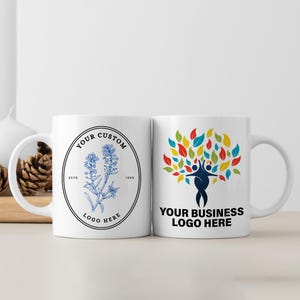 May include: Two white ceramic mugs with different designs. The mug on the left has a blue and white floral design with the text "Your Custom Logo Here" and "Est. 1990". The mug on the right has a colorful tree design with the text "Your Business Logo Here".