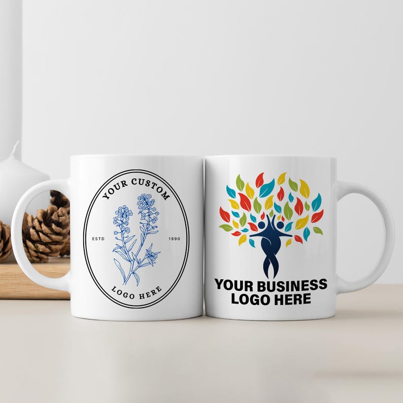 May include: Two white ceramic mugs with different designs. The mug on the left has a blue and white floral design with the text "Your Custom Logo Here" and "Est. 1990". The mug on the right has a colorful tree design with the text "Your Business Logo Here".