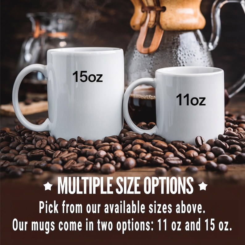 May include: Two white ceramic mugs with black text. The larger mug says "15oz" and the smaller mug says "11oz". Both mugs are sitting on a bed of coffee beans.