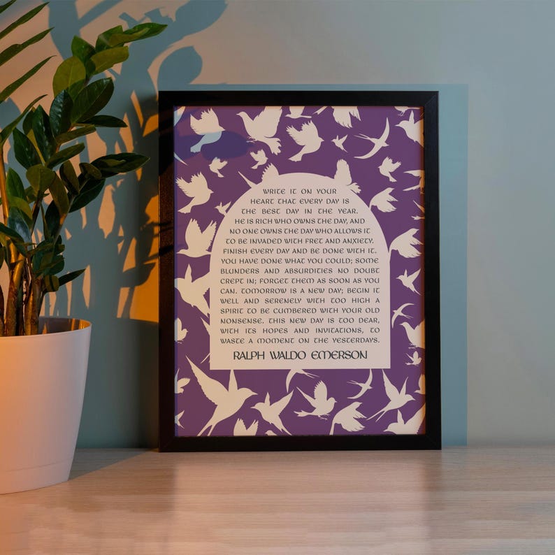 May include: A purple framed print with a white silhouette of birds on a purple background. The print features a quote by Ralph Waldo Emerson: "Write it on your heart that every day is the best day in the year. He is rich who owns the day, and no one owns the day who allows it to be invaded with fret and anxiety. Finish every day and be done with it. You have done what you could; some blunders and absurdities no doubt crept in; forget them as soon as you can. Tomorrow is a new day. Begin it well and serenely, with too high a spirit to be cumbered with your old nonsense. This new day is too dear, with its hopes and implications, to waste a moment on the yesterdays. - Ralph Waldo Emerson"