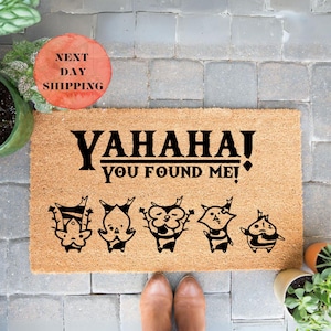 May include: A brown coir doormat with the text "YAHAHA! YOU FOUND ME!" in black. There are five black and white cartoon characters on the doormat.