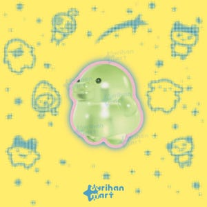 May include: A glossy, light green, rounded creature figurine with a small snout and black eyes, outlined in pink. The background is yellow with a blue halftone pattern of various small shapes and the text "durihan mart" at the bottom.